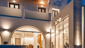 Una entrada de hotel moderna con un letrero de neón, una escalera y un puerta de cristal que da al interior.