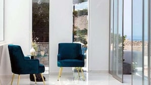 Un interior moderno con dos sillas azules, una pared de vidrio y vistas al exterior.