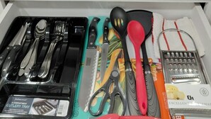 Un cajón de cocina con diversos utensilios y un organizador de cubiertos.