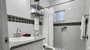 Un baño moderno con lavamanos, inodoro y zona de ducha.