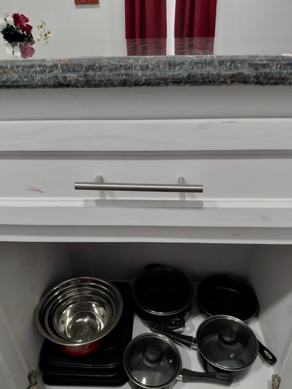 Una cocina con estufa, ollas y un cajón.