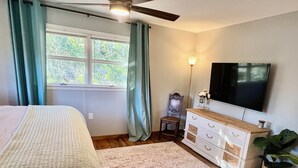 A bedroom with a bed, a dresser, a TV, a lamp, and a window with curtains. - Panther Creek Cozy Retreat (Newton)