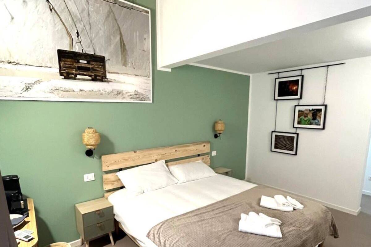 Ein Schlafzimmer mit Bett, Nachttischen, einer Lampe, einem Bild an der Wand und einem Fenster.