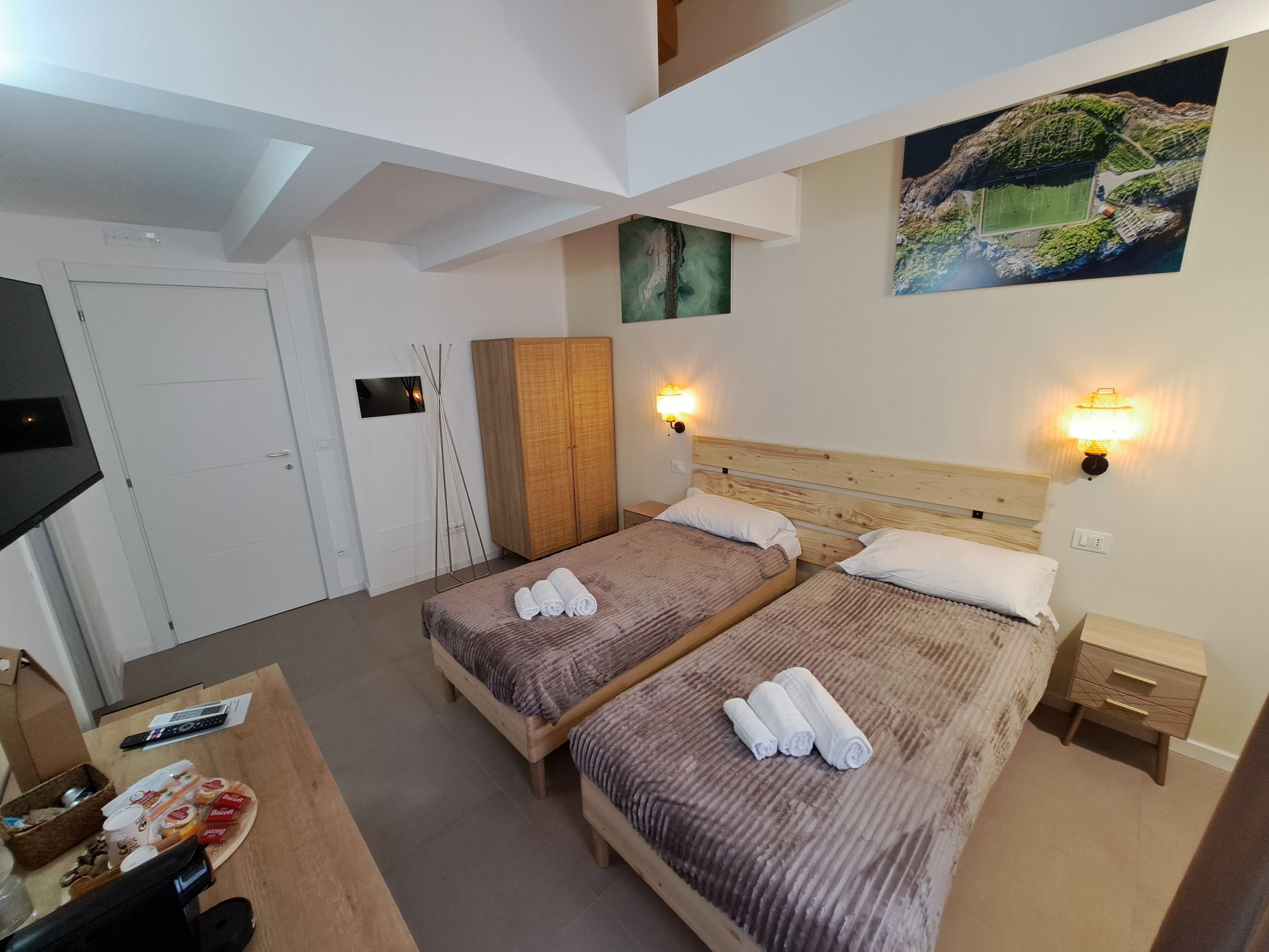 Une chambre d’hôtel avec deux lits, une télévision, une armoire en bois et un tableau au mur.