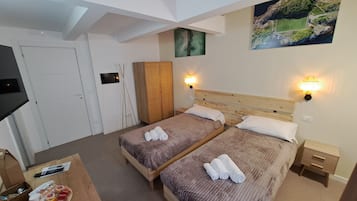 Une chambre d’hôtel avec deux lits, une télévision, une armoire en bois et un tableau au mur.