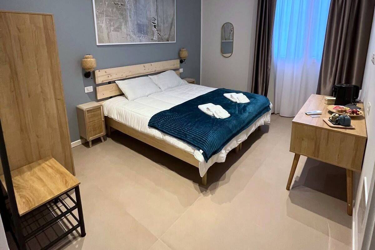 Ein modernes Hotelzimmer mit einem großen Bett, einem Schreibtisch, einem Kleiderschrank und einem Bild an der Wand.