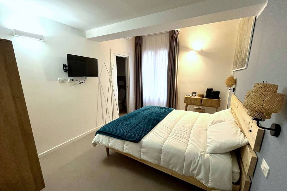 Ein Schlafzimmer mit Bett, Nachttisch, Lampe und Fernseher an der Wand.