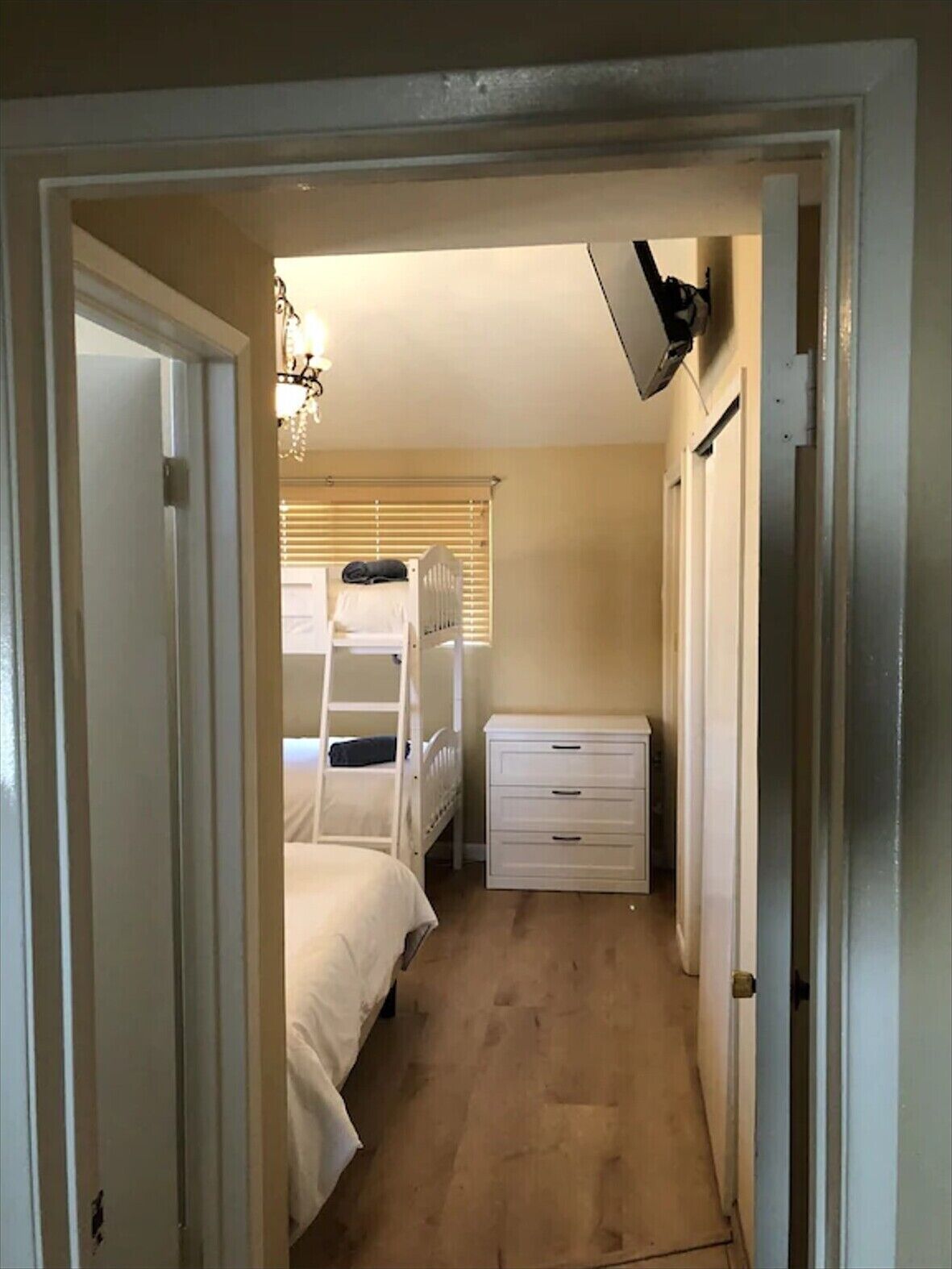Un pasillo estrecho con una cama litera, un aparador blanco y un ventilador de techo.
