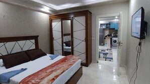 Una camera da letto con un letto, un armadio, una televisione e un bagno visibile tramite una porta aperta.