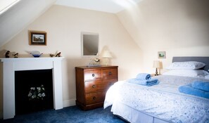 A bedroom with a bed, dresser, and fireplace. - Mill Cottage - a tranquil cottage location for 4 guests (Forres)
