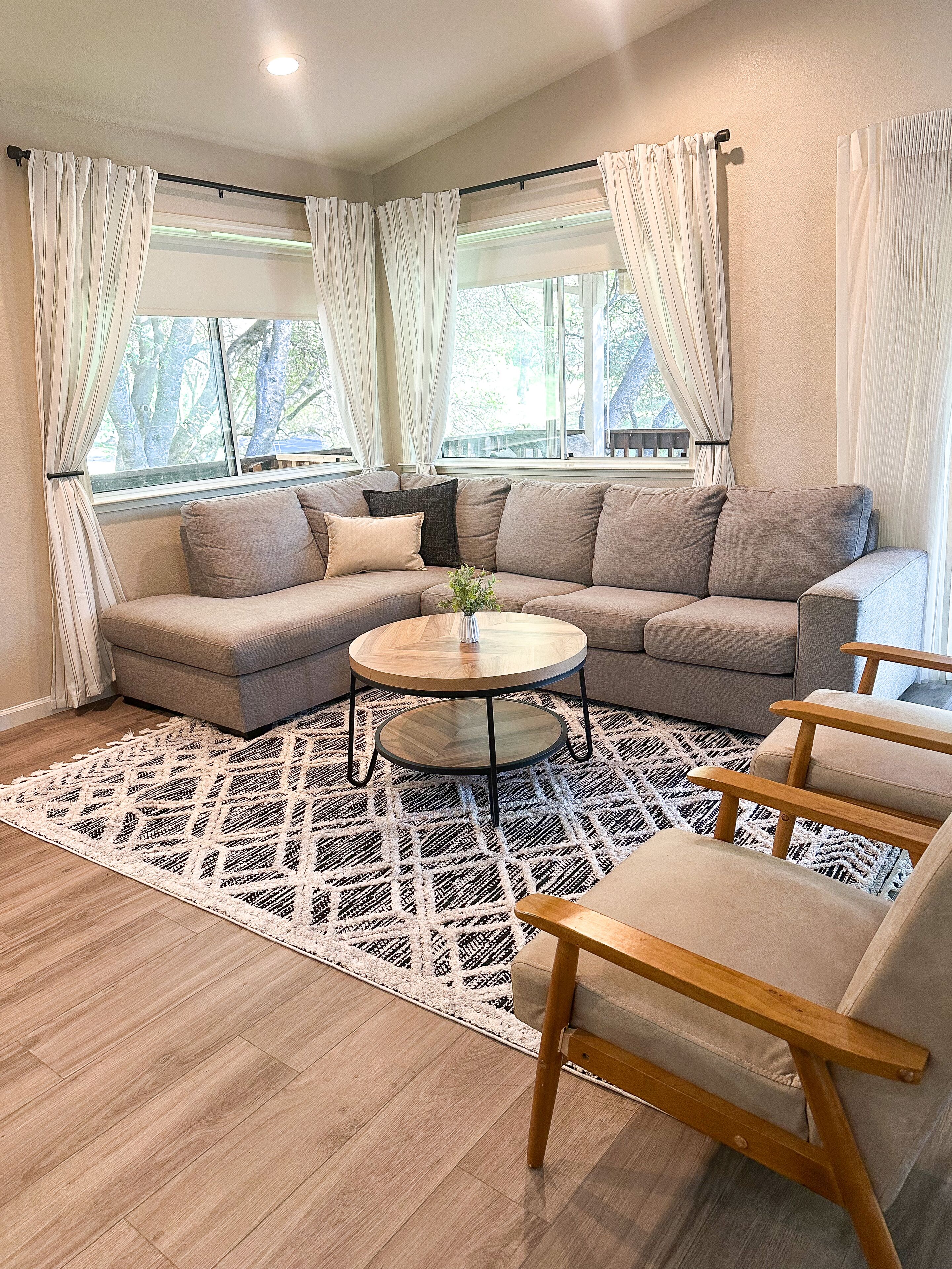 A living room with a sectional sofa, a round coffee table, and a patterned rug.
