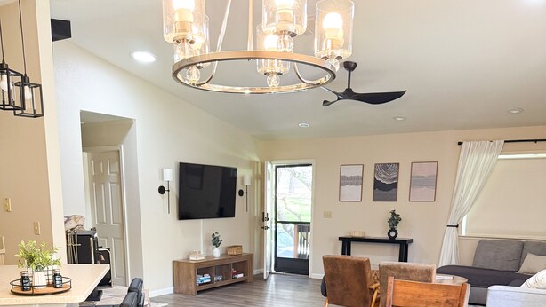 A spacious living area with a wooden dining table, a TV mounted on the wall, and a ceiling fan. - Recently Renovated 3 Bedroom house in Groveland with Central Heating and Air (Groveland)