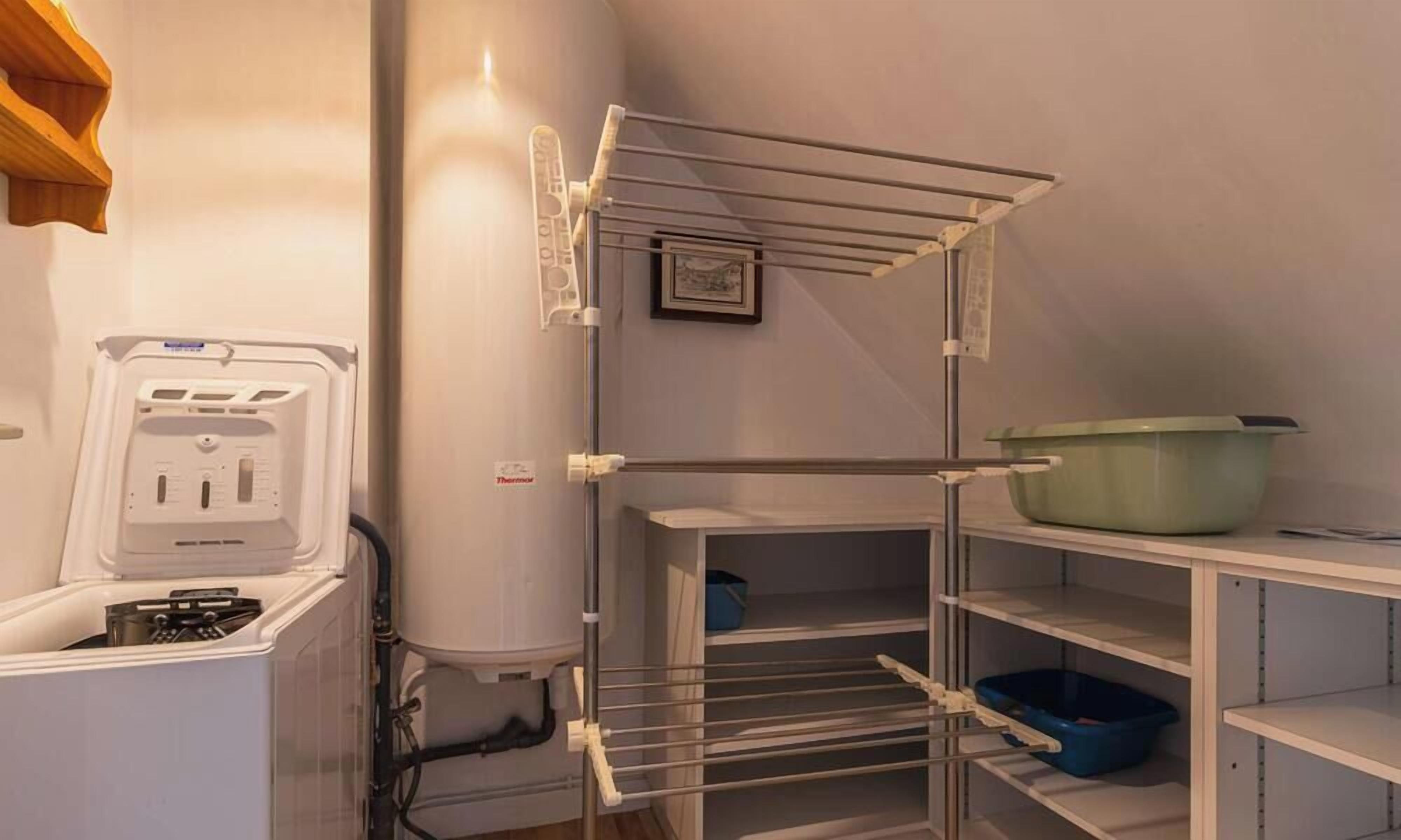 A compact kitchen with a built-in washer, a drying rack, and a green container on the countertop.