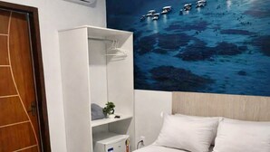 A hotel room with a bed, a wardrobe, a nightstand, and a wall mural of boats on water. - Pousada Doce Mar: Comfort and tranquility just steps from the beach. (Maragogi)
