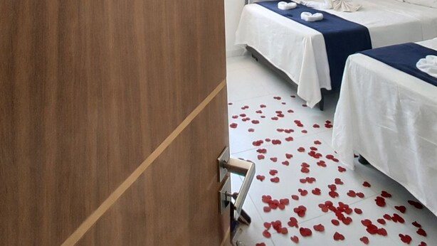 A hotel room with two beds, a painting of a beach, and a wooden door. - Pousada Doce Mar: Comfort and tranquility just steps from the beach. (Maragogi)