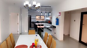 A modern kitchen with a central island, pendant lighting, and a dining area with a white table and yellow chairs. - Holiday Villa Marondera (Marondera)