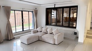 Una sala de estar moderna con un sofá modular, ventanas amplias y vistas al exterior.