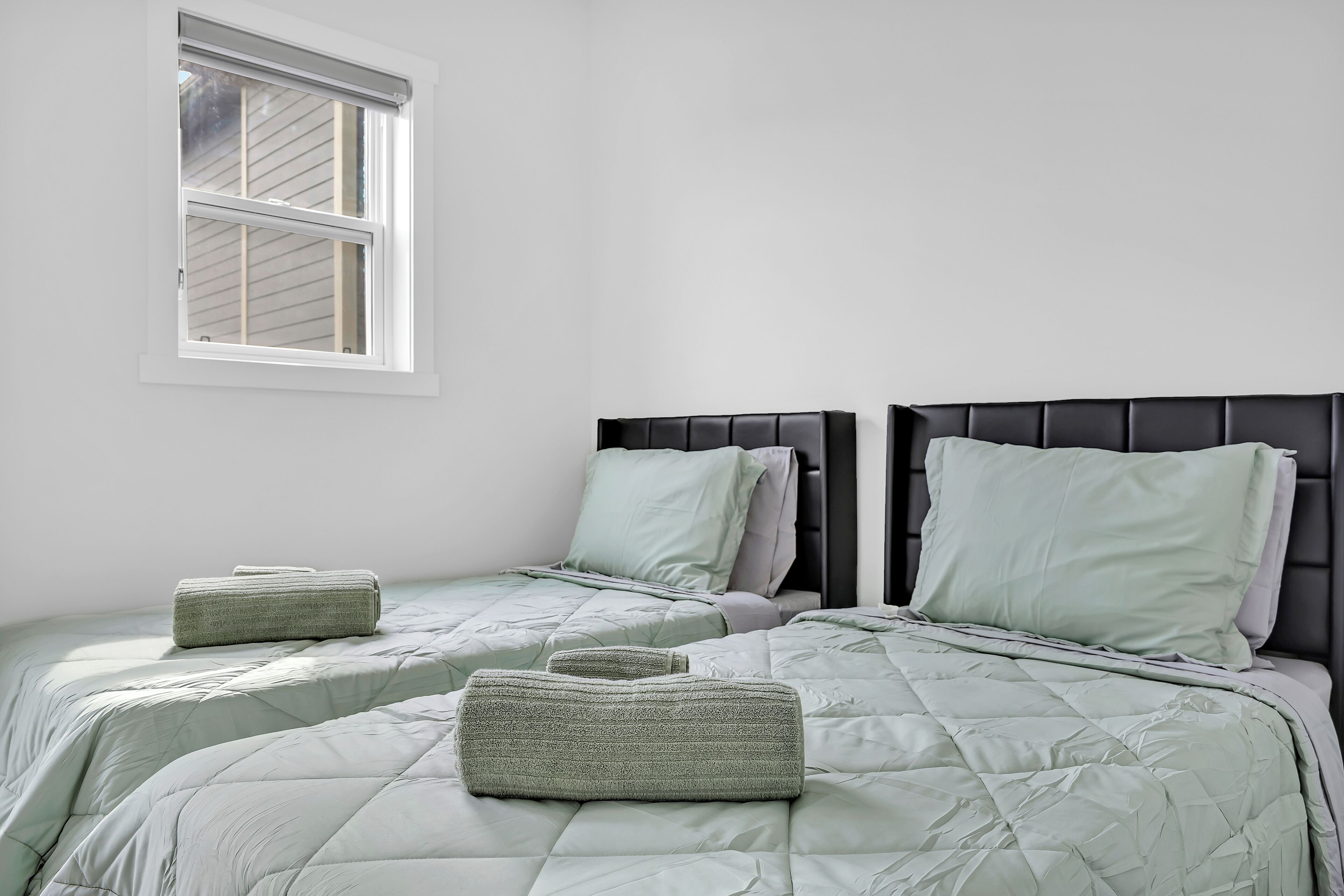 A bedroom with two beds, each with a headboard and pillows.