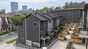 Ein mehrgeschossiges Wohnhaus mit Balkonen, einem Parkplatz und einer Reihe aus Holz-Pflanzkästen.