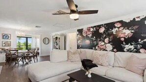 A living room with a white sectional sofa, a black coffee table, and a ceiling fan.