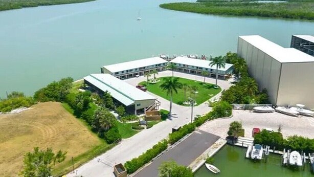 A hotel with a parking lot, a marina, and a view of a large body of water.