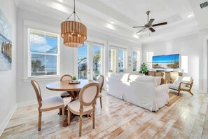 A spacious living area with a dining table, white sofas, and a ceiling fan. - Vacay on 30A by Stay on 30a (Inlet Beach)