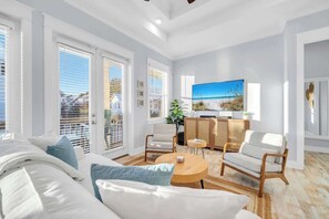 A bright living room with a sofa, chairs, a coffee table, and a TV. - Vacay on 30A by Stay on 30a (Inlet Beach)