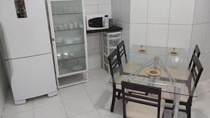 Una cocina compacta con refrigerador, microondas y un mueble de vidrio.
