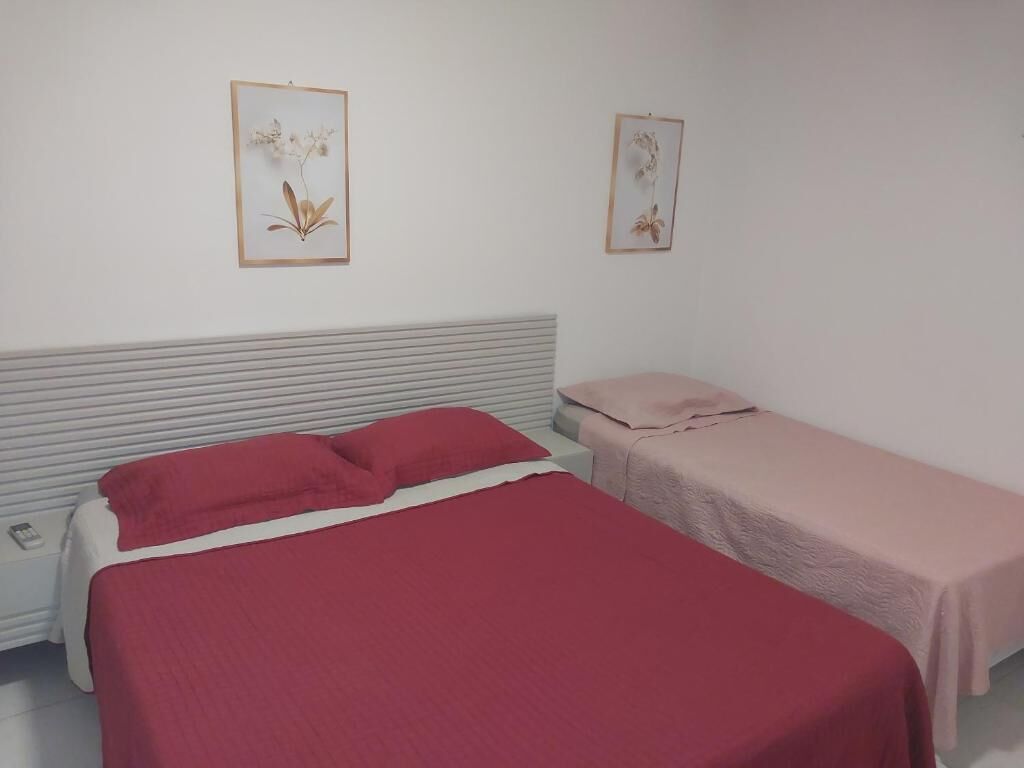Un dormitorio con una cama grande, una cama más pequeña y dos cuadros con motivos florales en la pared.