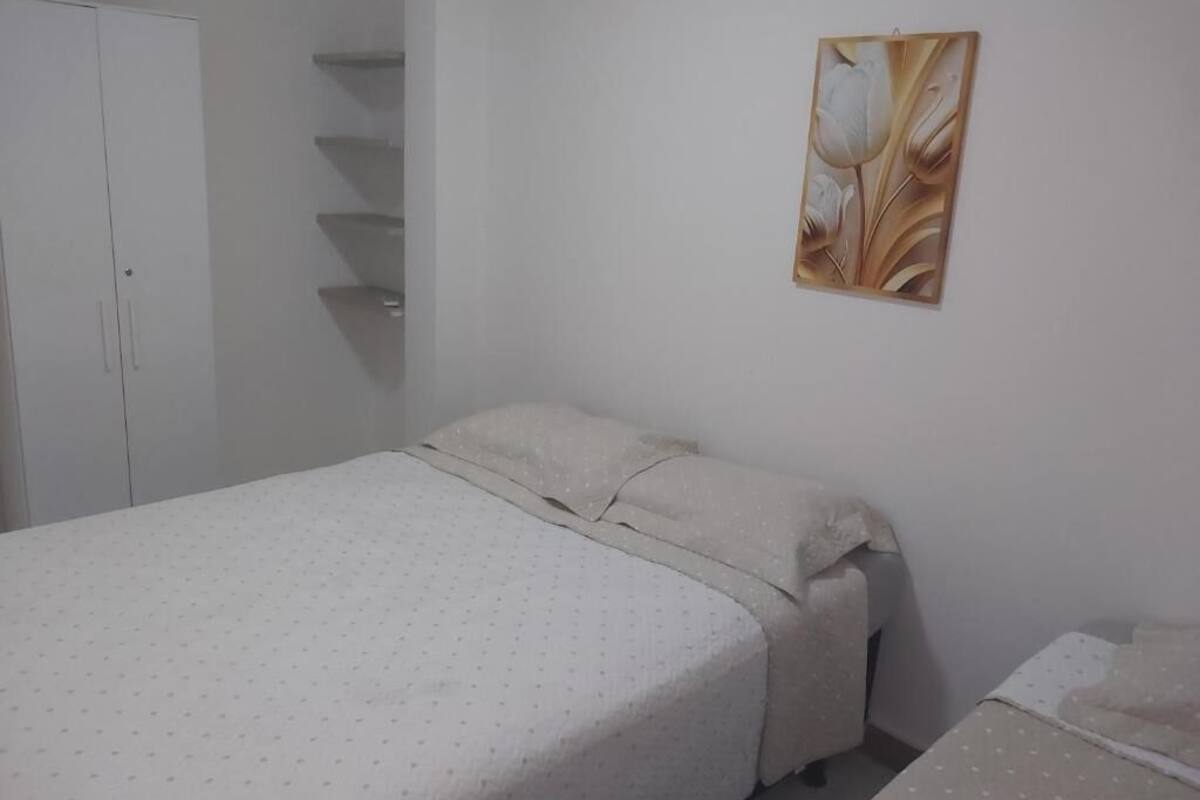 Un dormitorio con cama, armario y estante de pared.