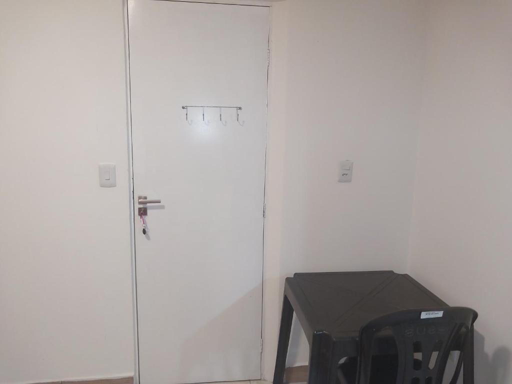 Um quarto com uma porta branca, uma pequena mesa e uma cadeira.