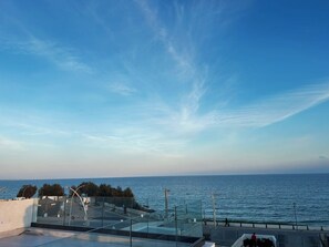 Blick auf die Küste mit blauem Himmel, einer Promenade und einem Gewässer.