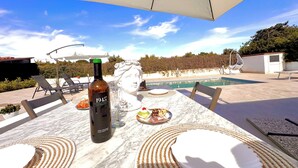 Un patio con una mesa para dos, una botella de vino y una escultura decorativa.
