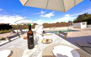 Eine Terrasse mit Tisch für Zwei, einer Weinflasche und einer dekorativen Skulptur.