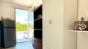 Una habitación con puerta de vidrio corredera que da a un espacio exterior, armario empotrado y refrigerador.