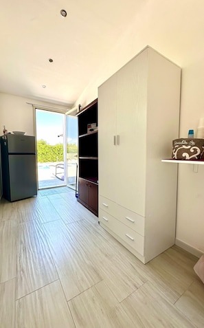Ein Zimmer mit einer Schiebeglasdoor zu einem Außenbereich, einem eingebauten Kleiderschrank und einem Kühlschrank.