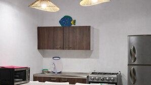 A modern kitchen with a white countertop, two pendant lights, a microwave, a stove, and a refrigerator. - Modern Apartment w Private Pool (Chiquimulilla)