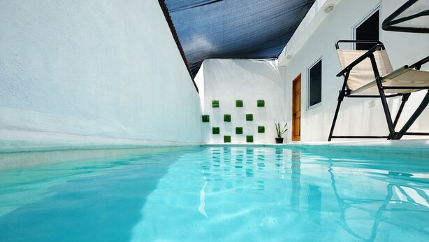 A clear blue pool with a white wall and a blue canopy overhead. - Modern Apartment with Private Pool (Chiquimulilla)