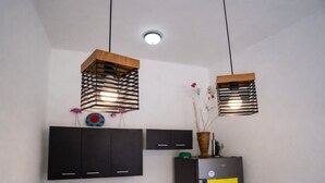 A kitchen with two hanging pendant lights, dark cabinets, a refrigerator, and a vase with flowers on top. - Modern Apartment with Private Pool (Chiquimulilla)