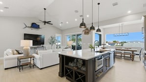 A modern kitchen with a central island, white cabinetry, and a dining area with a bench.