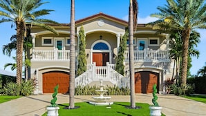 A two-story house with a central staircase, a front garage, and a well-manicured lawn with a fountain.