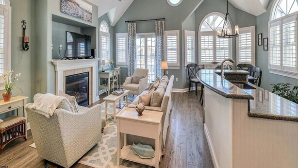 A spacious living area with a fireplace, a sofa, a dining table, and a kitchen area with a bar. - Spectacular Southend 3BR Condo • Sleeps 7 • Rooftop Deck & Parking (Ocean City)