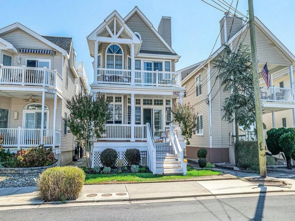 A two-story house with a balcony, a front porch, and a staircase leading to the entrance.