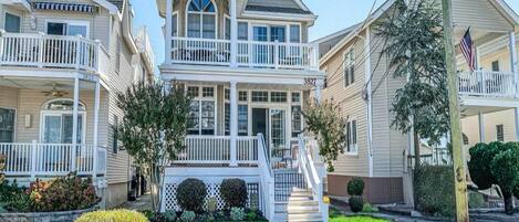 A two-story house with a balcony, a front porch, and a staircase leading to the entrance.