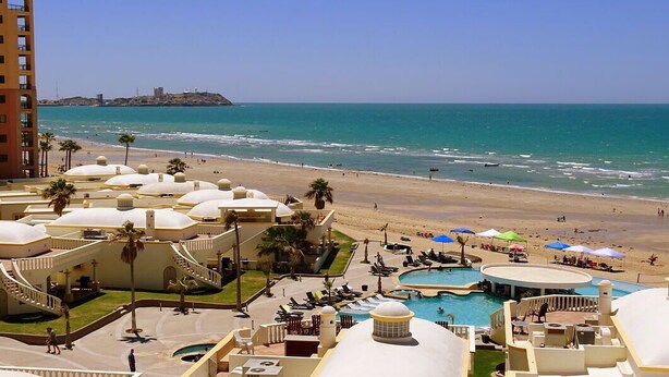 Resort com piscina, praia e vista para o mar.