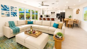 A modern living room with a sectional sofa, a dining area, and a kitchen in the background. - Luxe Pool Retreat:  Heated Pool, Game Room, Sleeps 14 (Fort Lauderdale)