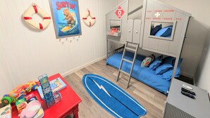 A child's bedroom with bunk beds, a surfboard, and a poster saying "Surf's Up!". - Fort Myers Coastal Retreat Hot Tub Yard Games (Fort Myers)
