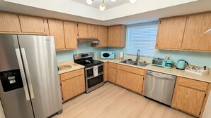 A modern kitchen with wooden cabinets, stainless steel appliances, and a skylight. - Retro Coastal Fort Myers Retreat Spa Fire Pit (Fort Myers)