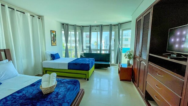 Ein Hotelzimmer mit zwei Betten, einem Fernseher und Blick aufs Meer.