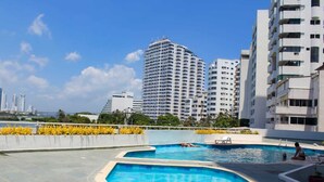 Ein Hotel mit Schwimmbad, umgeben von Hochhäusern und Palmen.